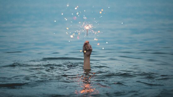Hand with sparkler coming out of water