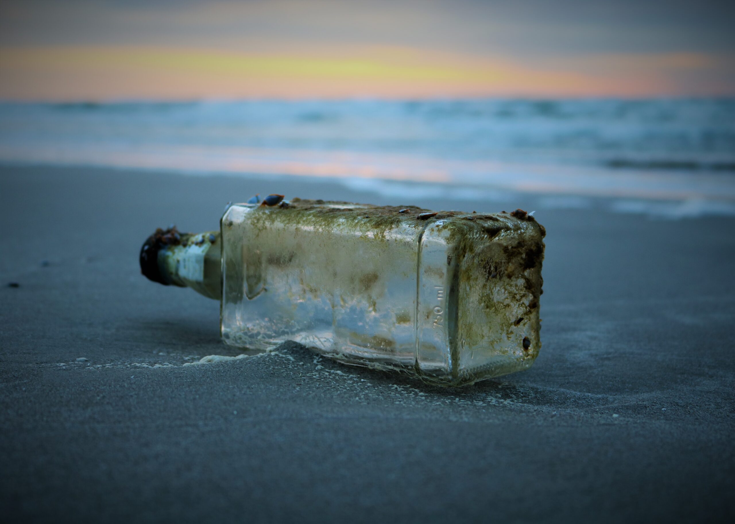 Empty bottle on a sandy beach for blog post on RosaEmilia